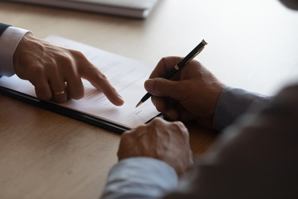 Hands of lawyer pointing at paper for businessman signing contract.
