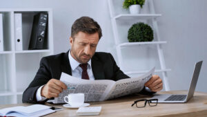 a businessman looking worried and reading a a newspaper
