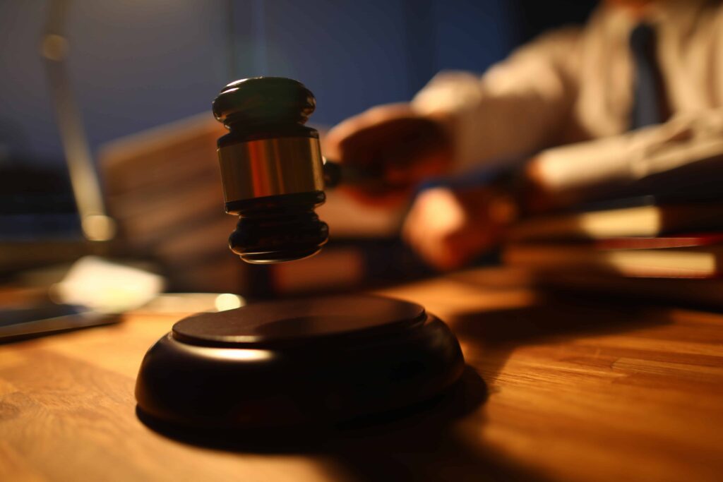 Judge striking gavel on wooden desk in courtroom symbolizing justice and legal decision.
