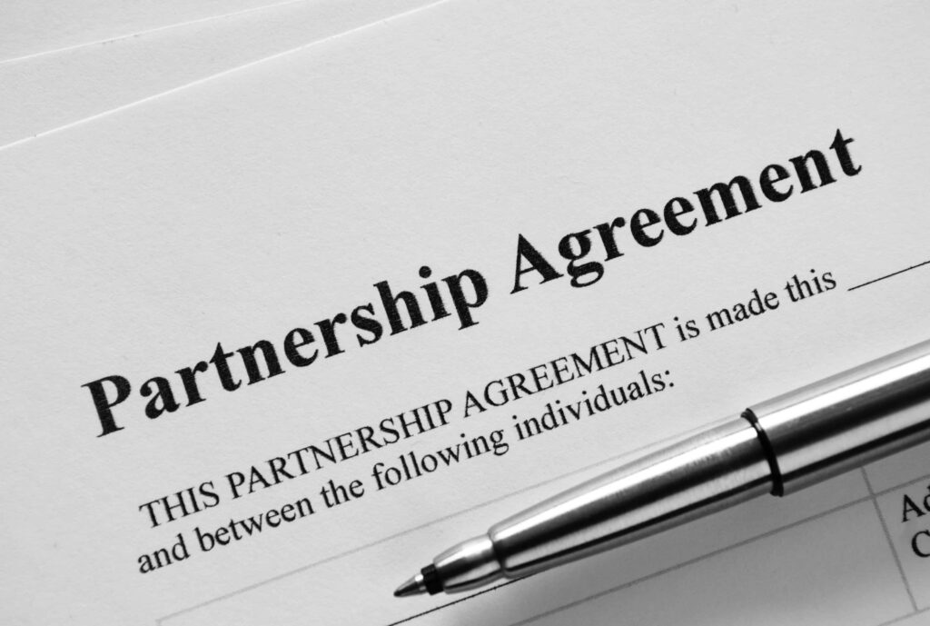 Close-up of a partnership agreement document with a pen ready for signature.
