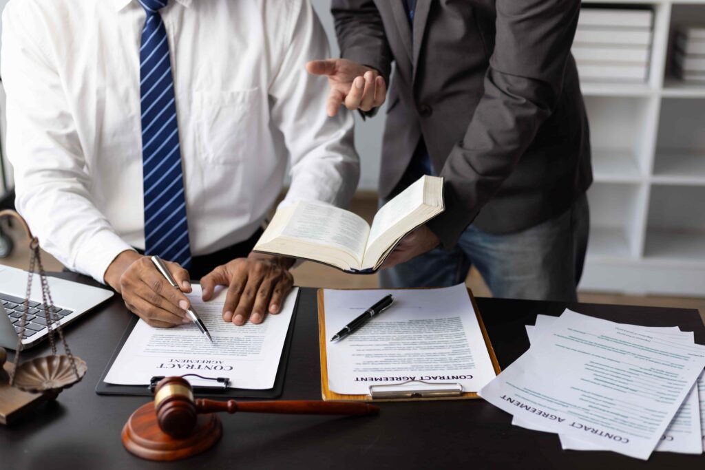 Business lawyer reviewing and signing contract agreement documents with client in office. Business lawyer reviewing and signing contract agreement documents with client in office.