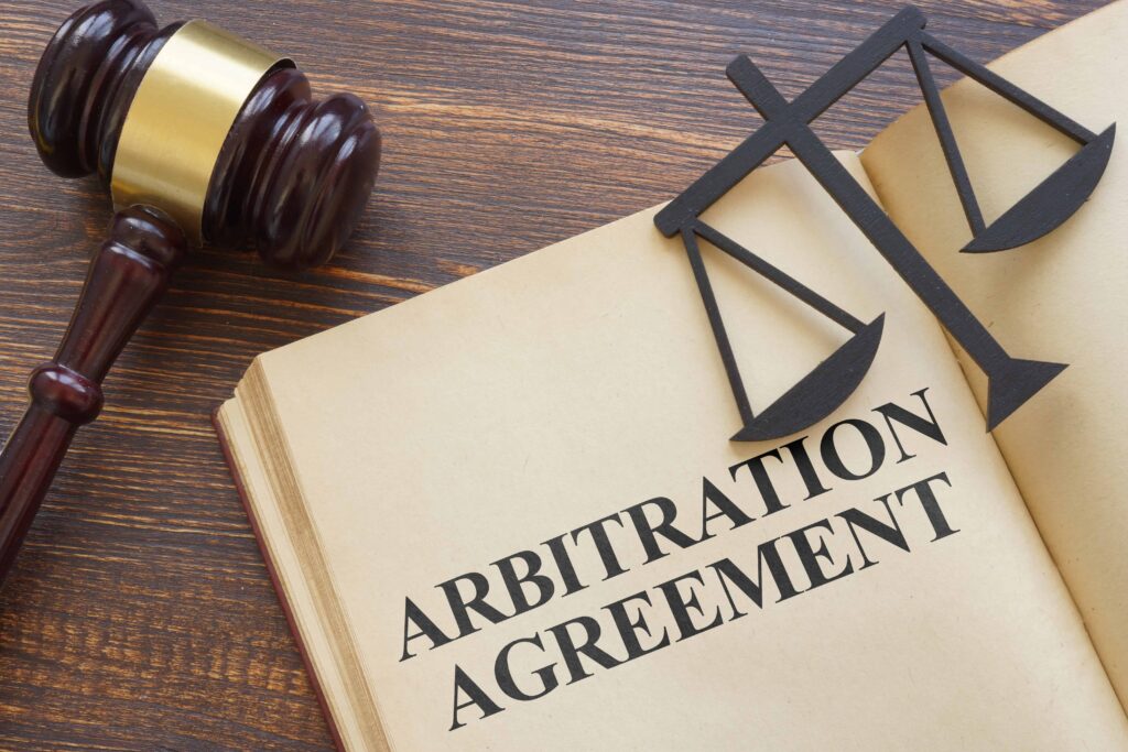 Arbitration agreement document with judge&rsquo;s gavel and scales of justice on wooden table.