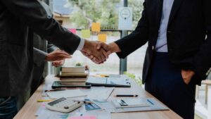 Business professionals shaking hands after successful contract agreement in office meeting.