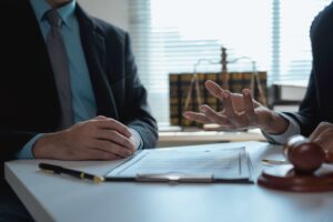 Lawyer consulting with client over legal documents in office with gavel and justice scales on desk.