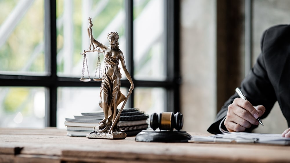 Business defamation lawsuit strategy represented by Lady Justice and attorney reviewing legal documents
